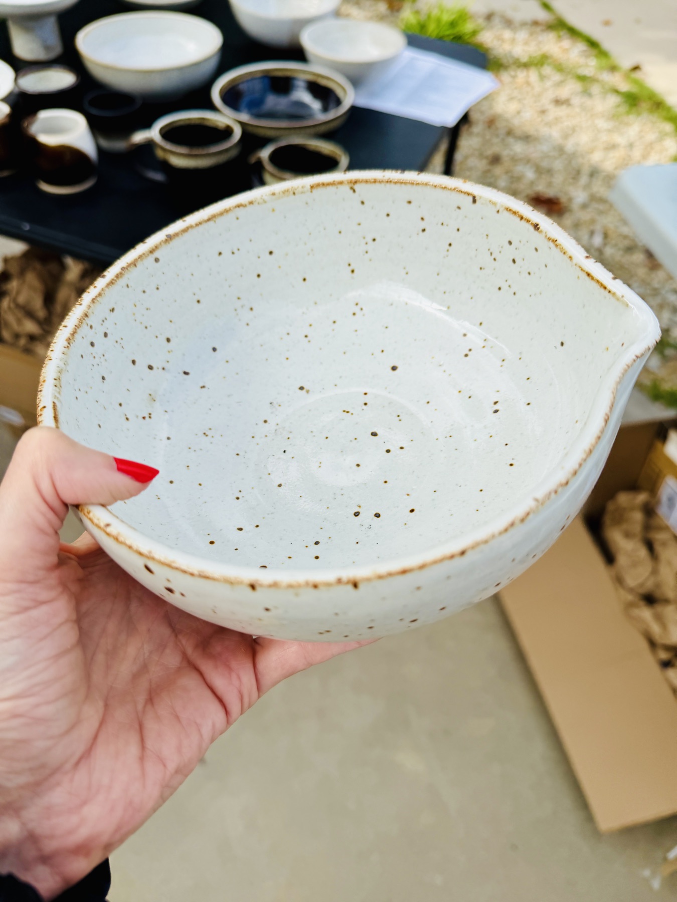 A speckled white stoneware bowl with a pour spout, held in hand