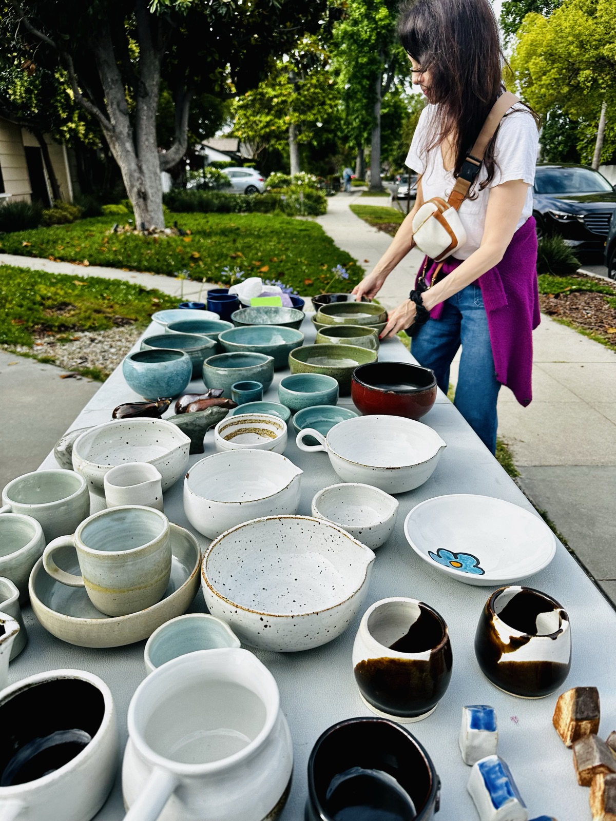 A table covered with handmade bowls, mugs and cups in cream and celadon glazes